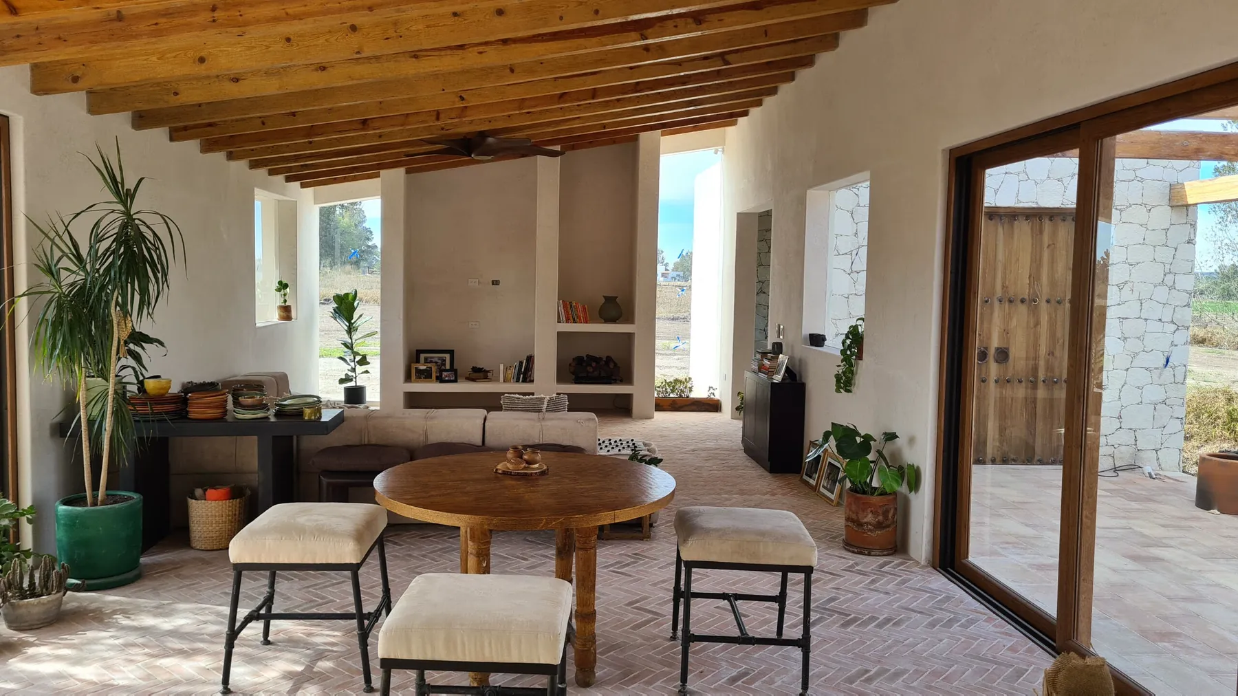 Interior con vigas de madera a la vista, muros de cantera y puertas abiertas al jardín